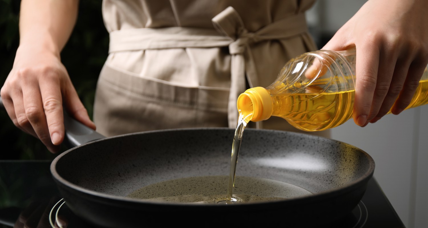 woman,pouring,cooking,oil,from,bottle,into,frying,pan,,closeup